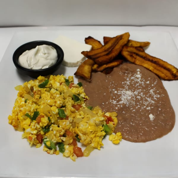 Mexican breakfast plate with scrambled eggs, refried beans, fried plantains, cheese, and sour cream.