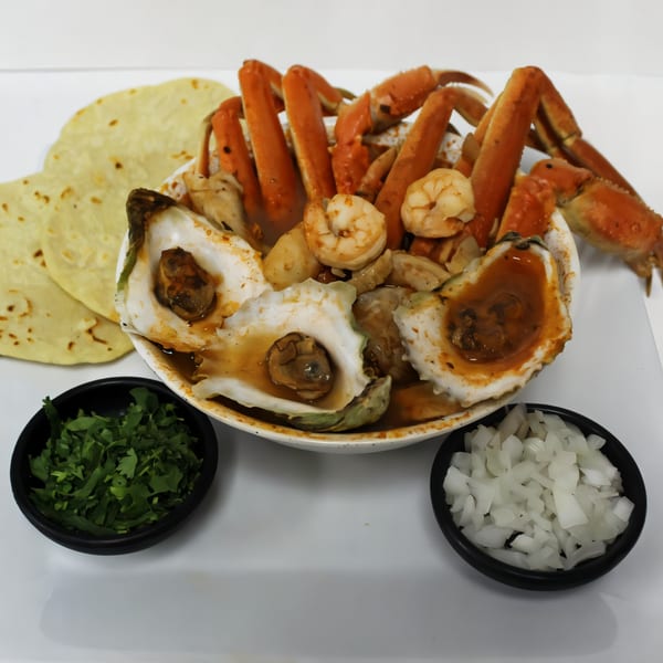 A large bowl of La Bamba's seafood soup with crab legs, shrimp, oysters, and tortillas.