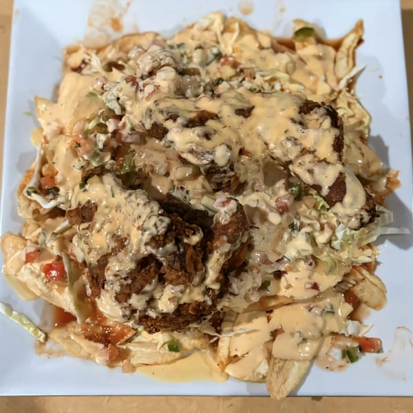La Bamba's Mexican dish features fried chicken, creamy sauce, and fresh vegetables on a white plate.